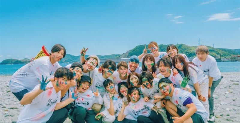 海辺でオリジナルTシャツを着て笑顔の若者たち